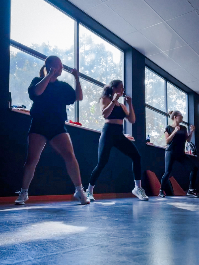 Cours collectif cardio, personne debout en train de suivre un cours en sautant d'avant en arrière